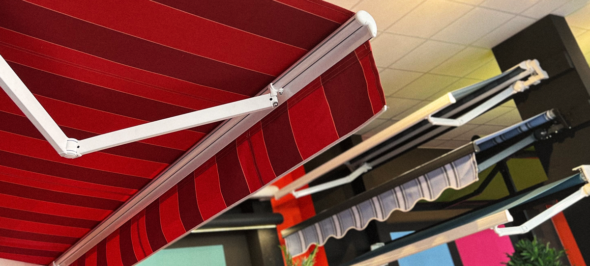 Toiles pour stores bannes - Conseils pour le choix de la toile Quatre stores bannes exposés dans notre showroom